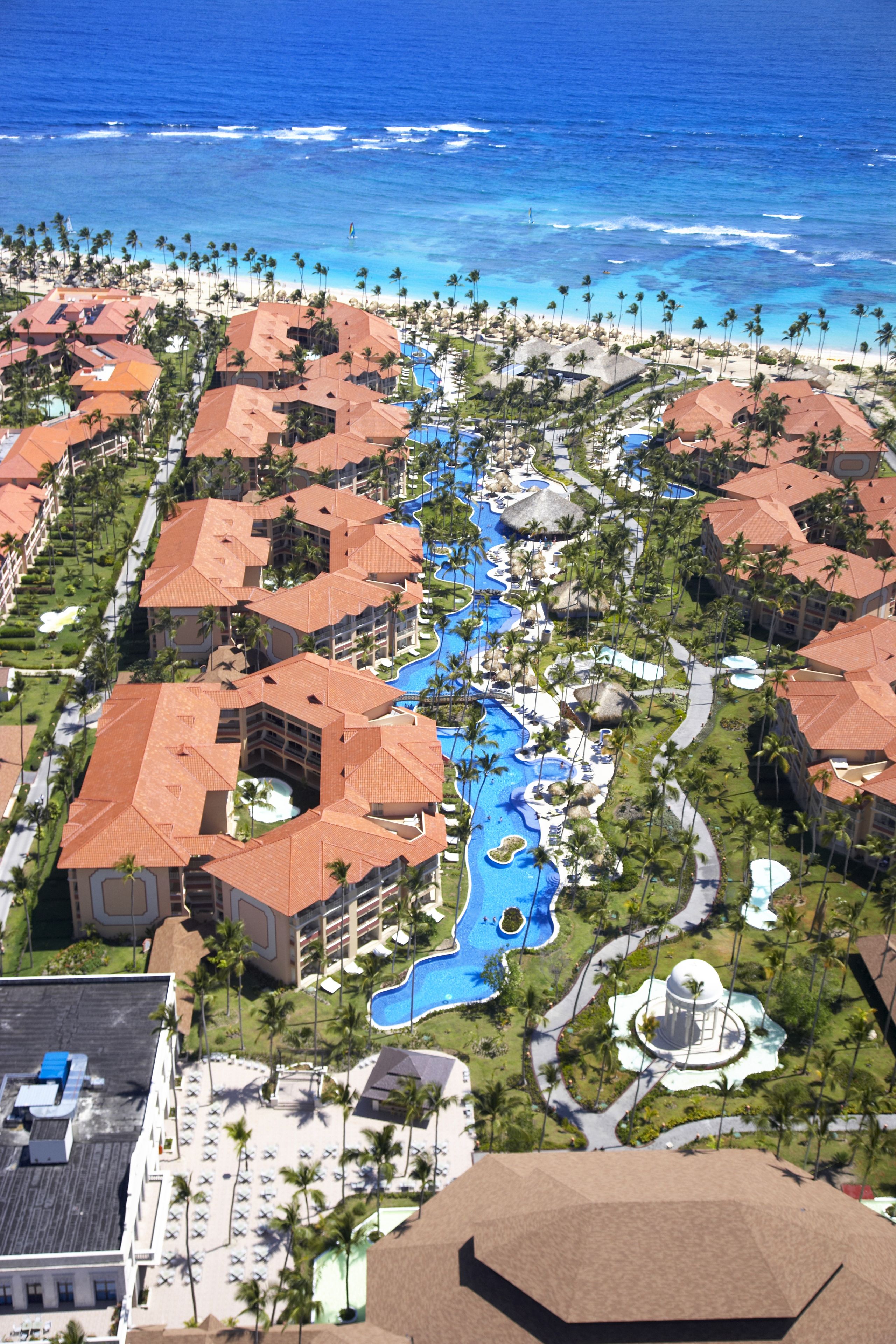 A resort with multiple buildings, a central swimming area, and a beach.