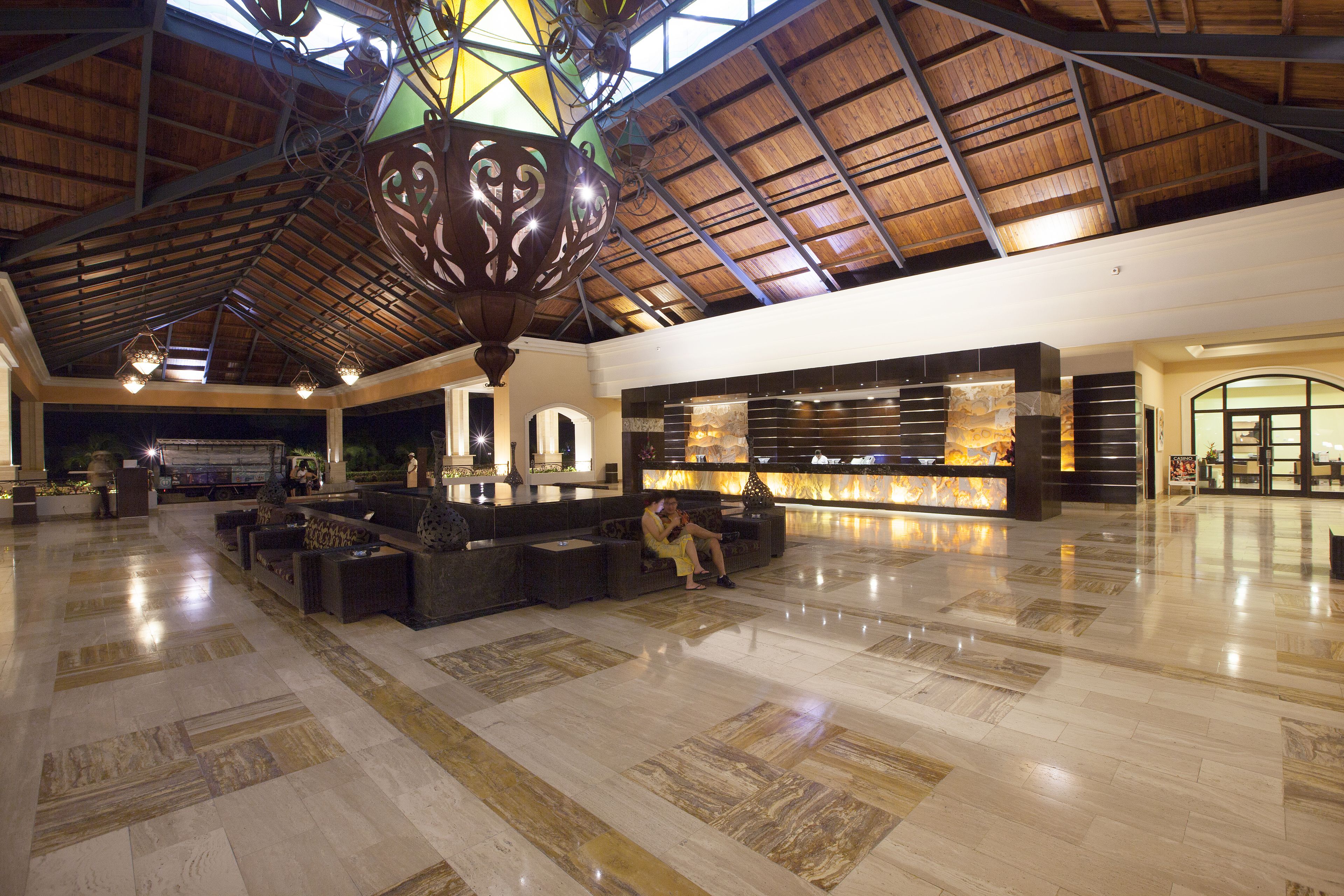 A spacious lobby with a high ceiling, a central seating area, and a reception desk.