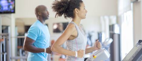 Un gimnasio con cintas de correr y equipo de ejercicio.