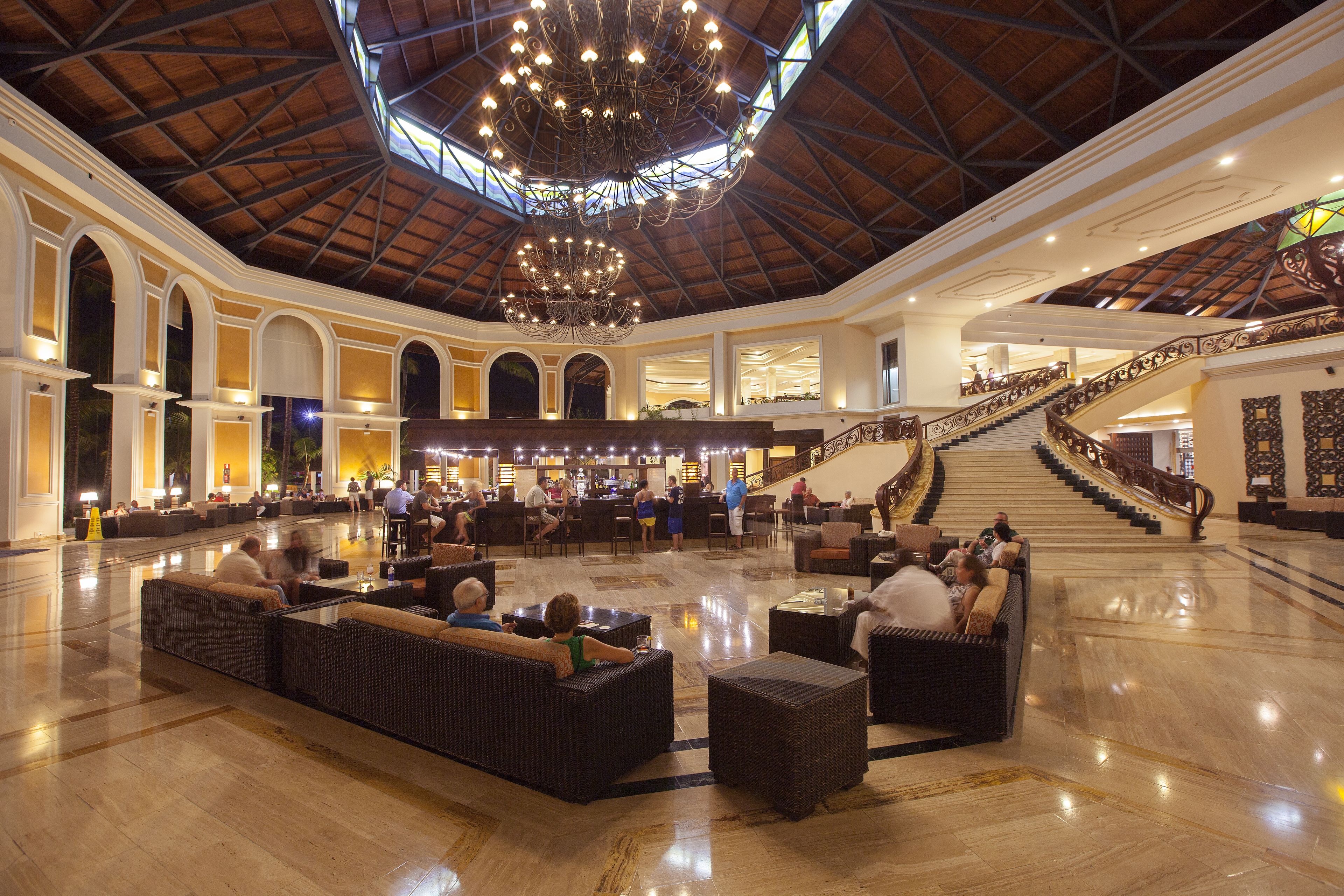 A spacious lobby with a high ceiling, a grand staircase, and seating areas.
