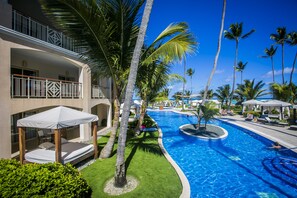 A resort with a swimming pool, palm trees, and a covered outdoor seating area. - Majestic Elegance Punta Cana - All Inclusive (Punta Cana)
