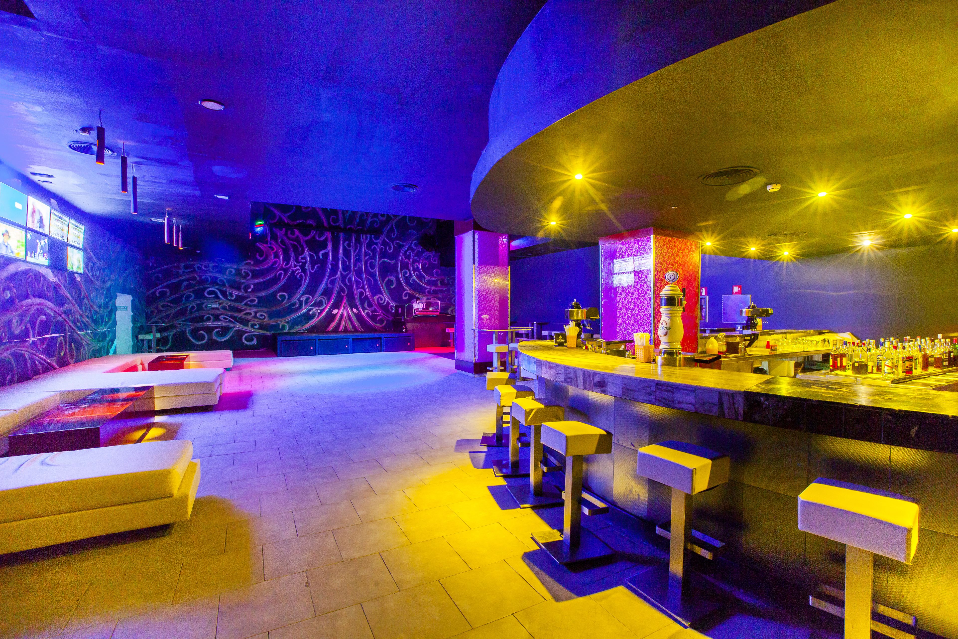 A bar area with a counter, stools, and a patterned wall.