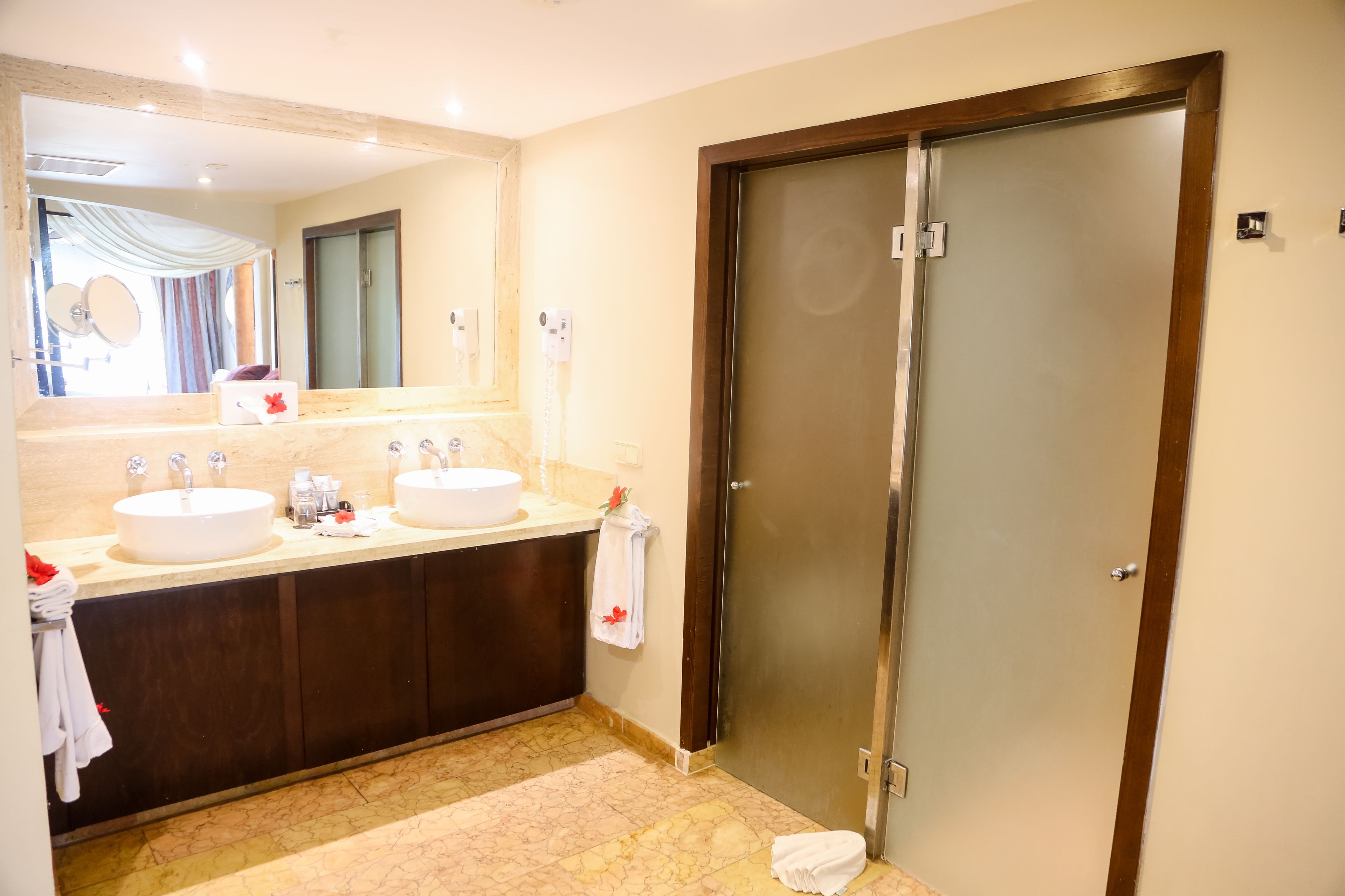 A bathroom with two sinks, a large mirror, and a frosted glass door.