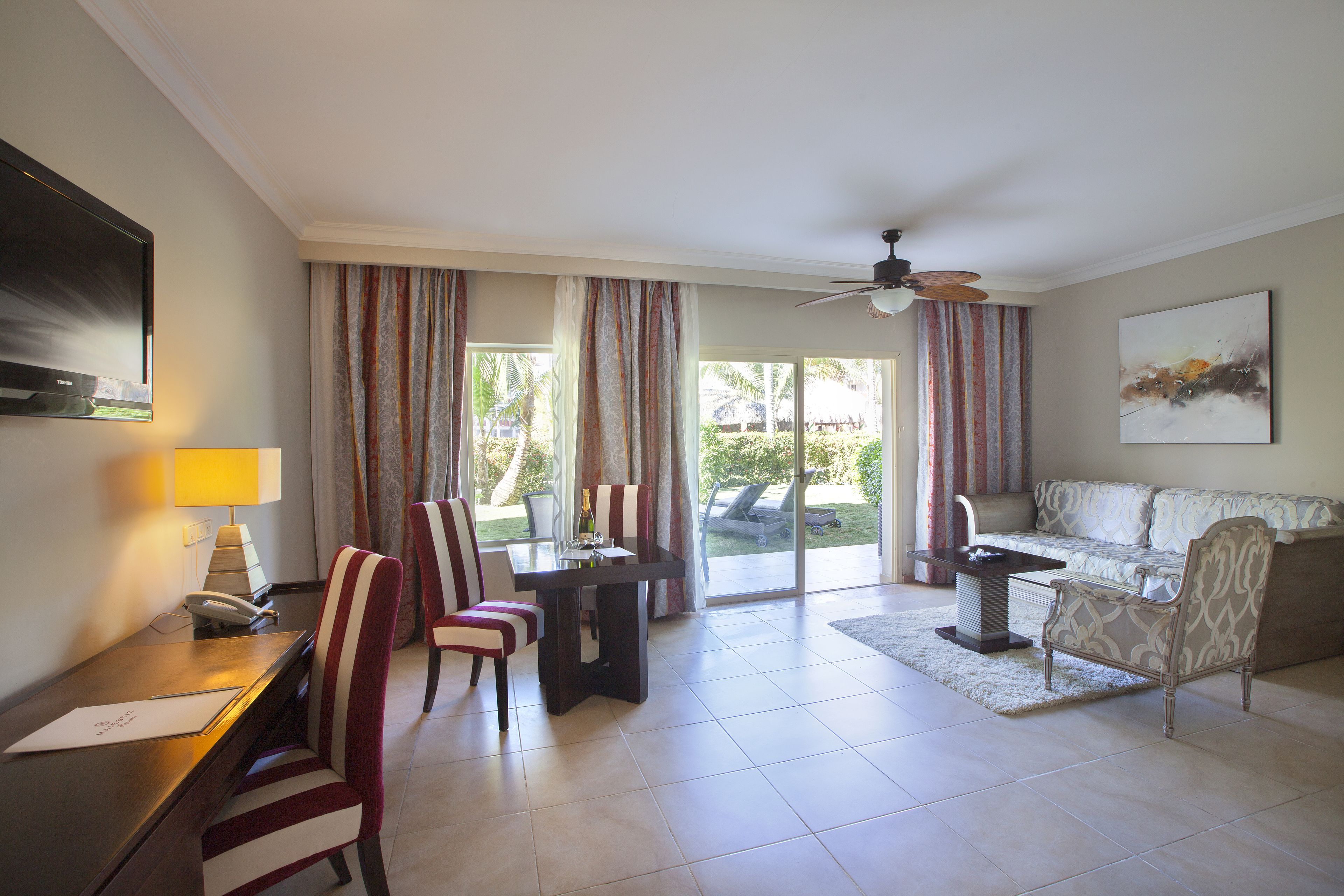 A spacious living room with a sofa, chairs, a dining table, and a TV.