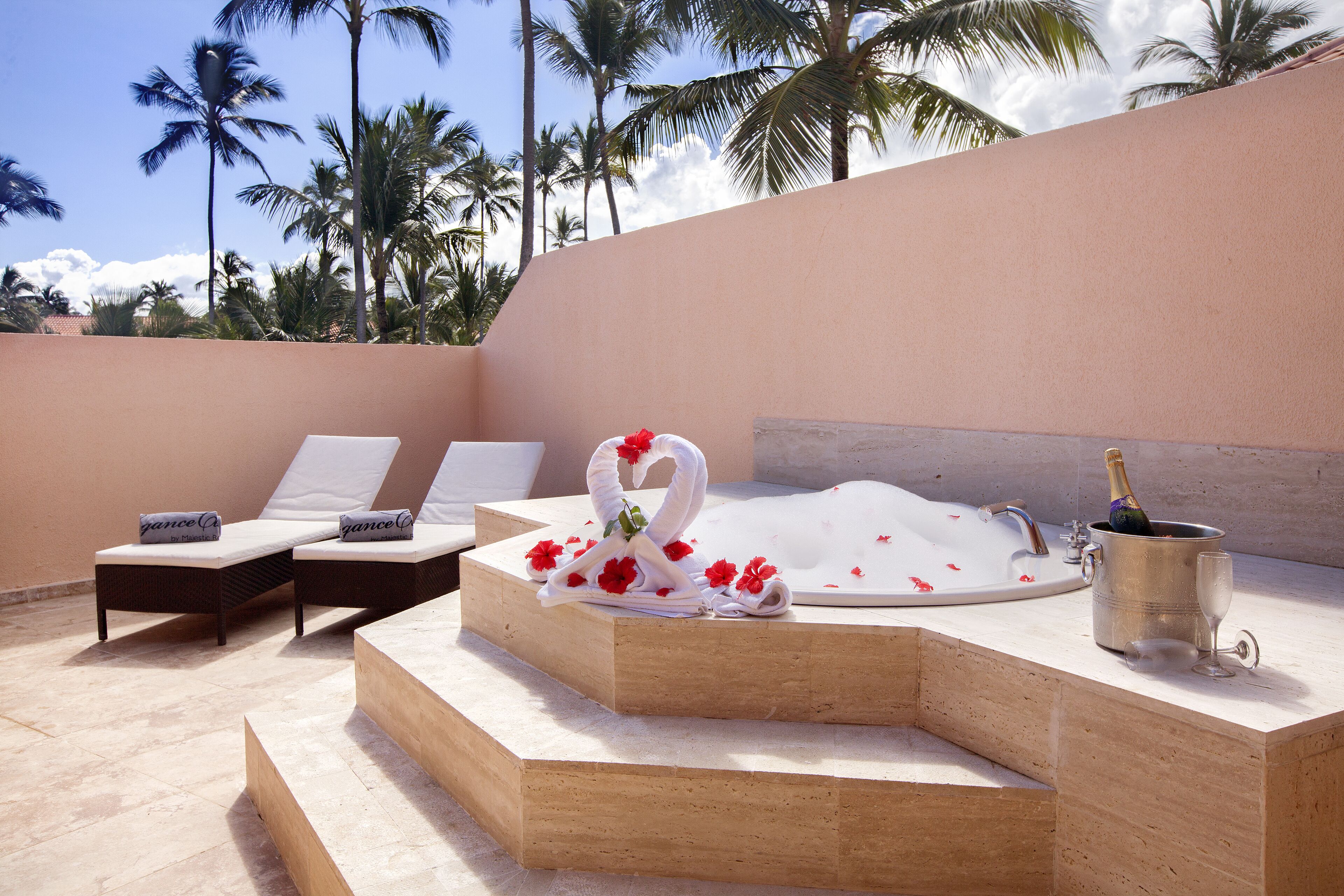 A spa area with a hot tub, lounge chairs, and a champagne bottle.