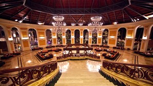 A grand lobby with a central staircase, ornate railings, and chandeliers. - Majestic Elegance Punta Cana - All Inclusive (Punta Cana)