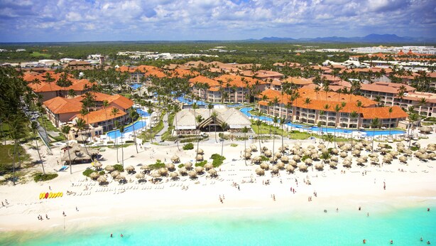 Un complejo turístico con varias edificaciones, una playa y una zona de piscina.