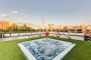 Una piscina en la azotea con vistas a una torre histórica y edificios circundantes.