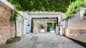 La entrada a un hotel con fachada de piedra, un camino adoquinado y un letrero que dice "Cinemusio Hotel".