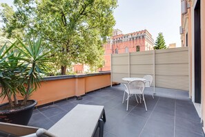 Un balcon avec un pot de fleurs, une table et des chaises.