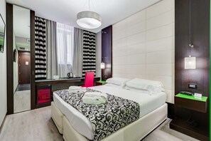 Une chambre d’hôtel comprenant un lit, un bureau, un miroir, une armoire et une salle de bain.