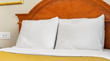 A neatly made bed with white pillows and a yellow and blue bedspread.