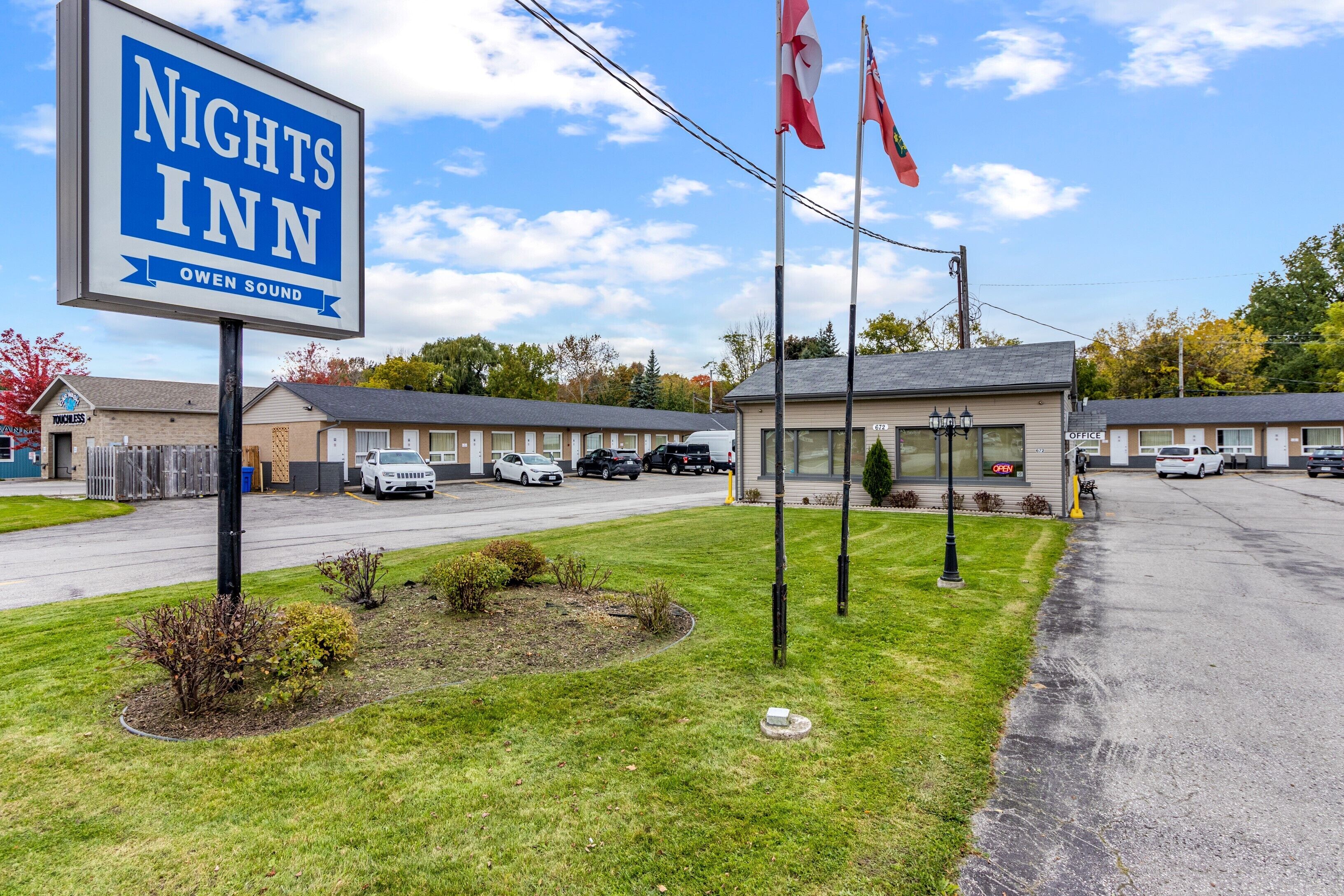 Um motel com uma placa que diz "Nights Inn Owen Sound" e algumas bandeiras.