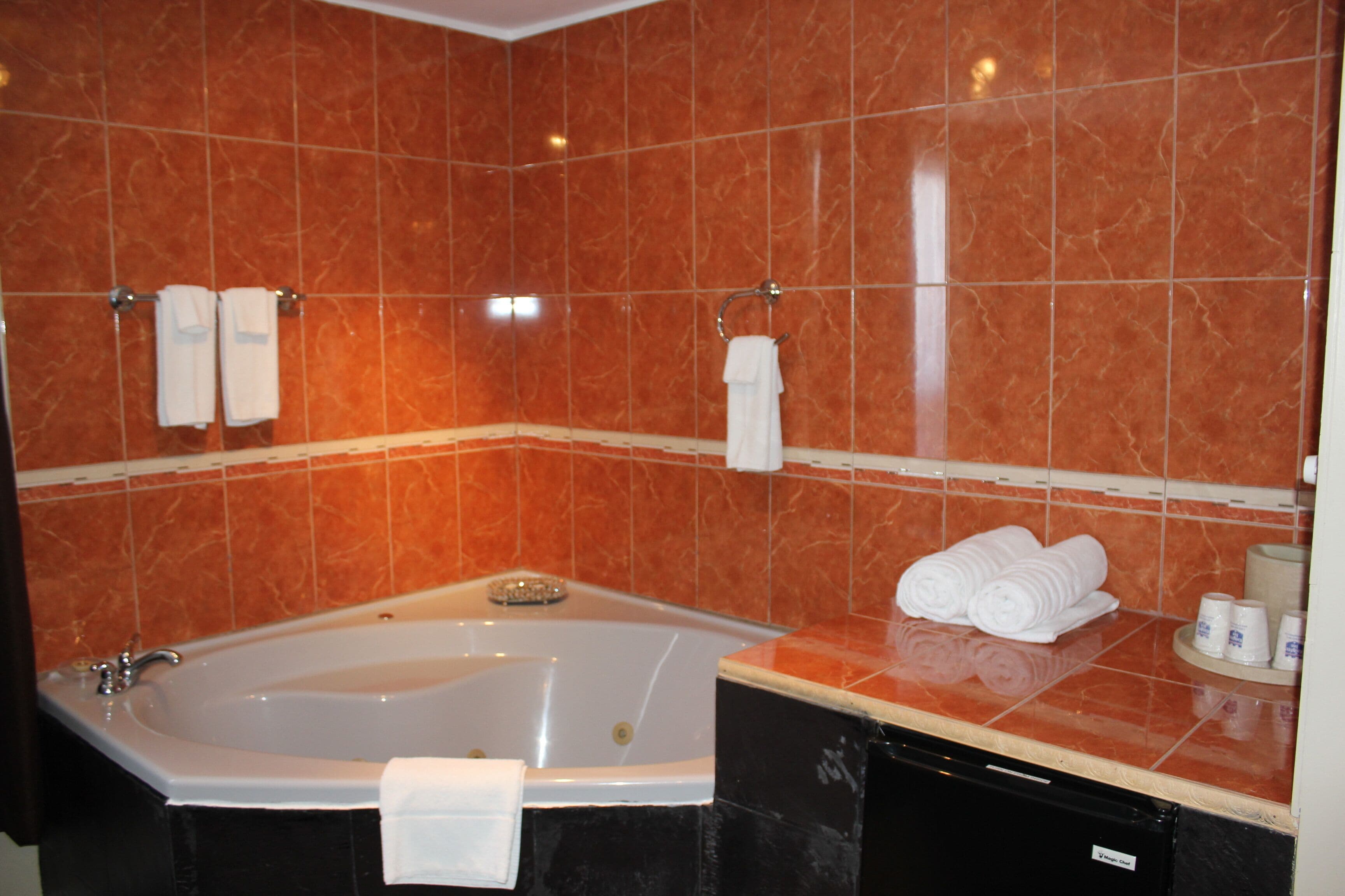 A bathroom with a large bathtub, two towel racks, and neatly folded towels on the counter.