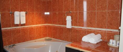 Un baño con una bañera grande, dos toalleros y toallas dobladas ordenadamente sobre el mostrador.