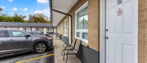 A motel with a row of rooms, a covered parking area, and a no smoking sign on the door.