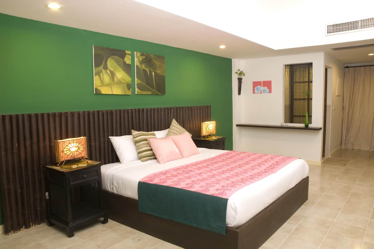 Une chambre avec un grand lit, des murs verts et une fenêtre donnant sur un beau paysage.
