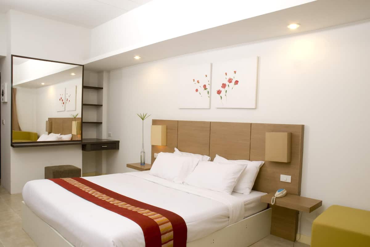 Une chambre d’hôtel moderne avec un grand lit, une table de chevet, un miroir et des œuvres d’art accrochées au mur.
