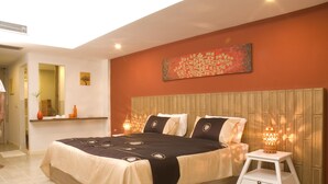 A bedroom with a large bed, bedside lamps, a nightstand, a mirror, and a decorative wall piece. - Nantra De Boutique (Pattaya)