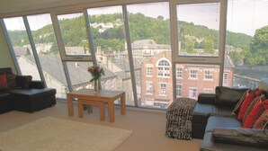 Ein geräumiges Wohnzimmer mit großen Fenstern, einem Sofa, einem Couchtisch und einem Teppich.