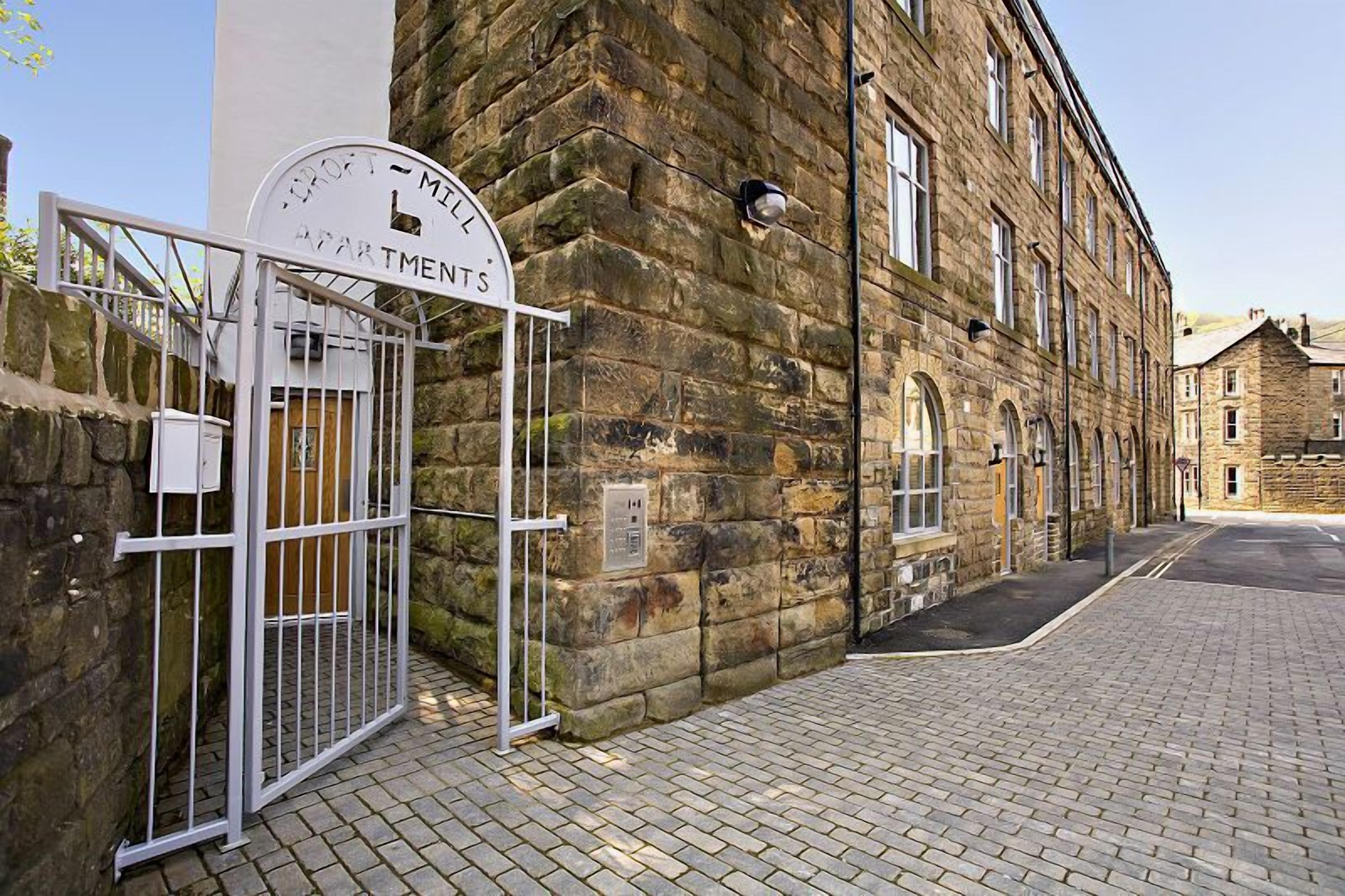 A stone building with a sign reading "TROF 1 - MELL APARTMENTS" and a gated entrance.
