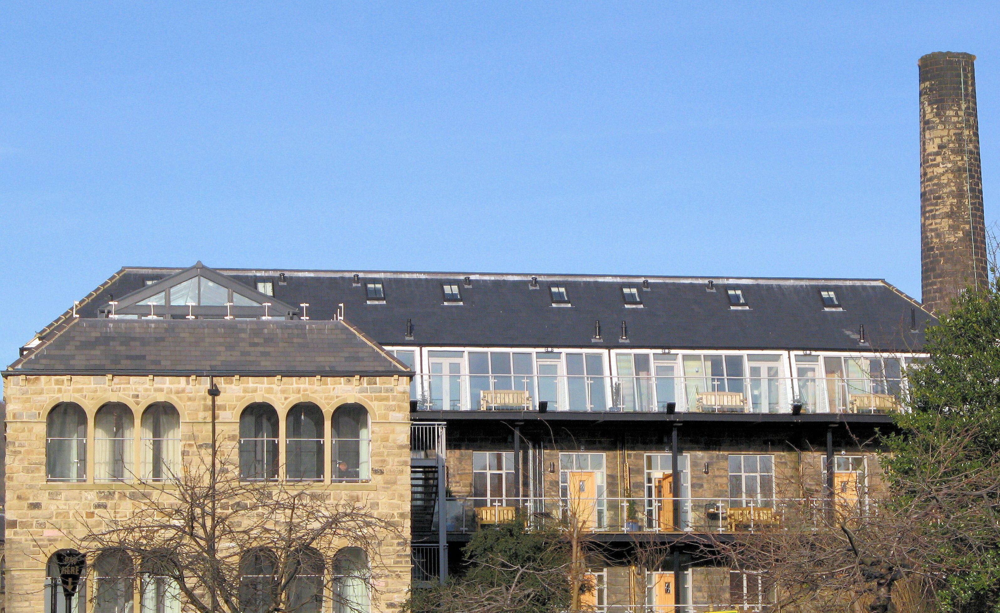 A historic building with a stone facade, large windows, and a tall chimney.
