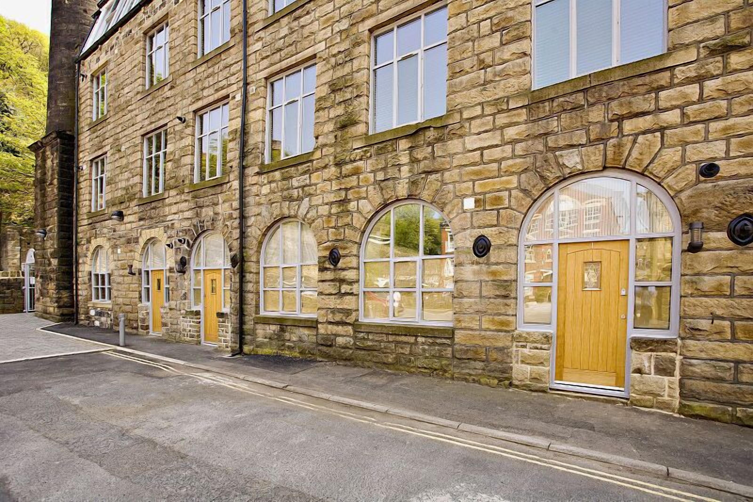 A stone building with multiple windows and doors, featuring a mix of arched and rectangular designs.