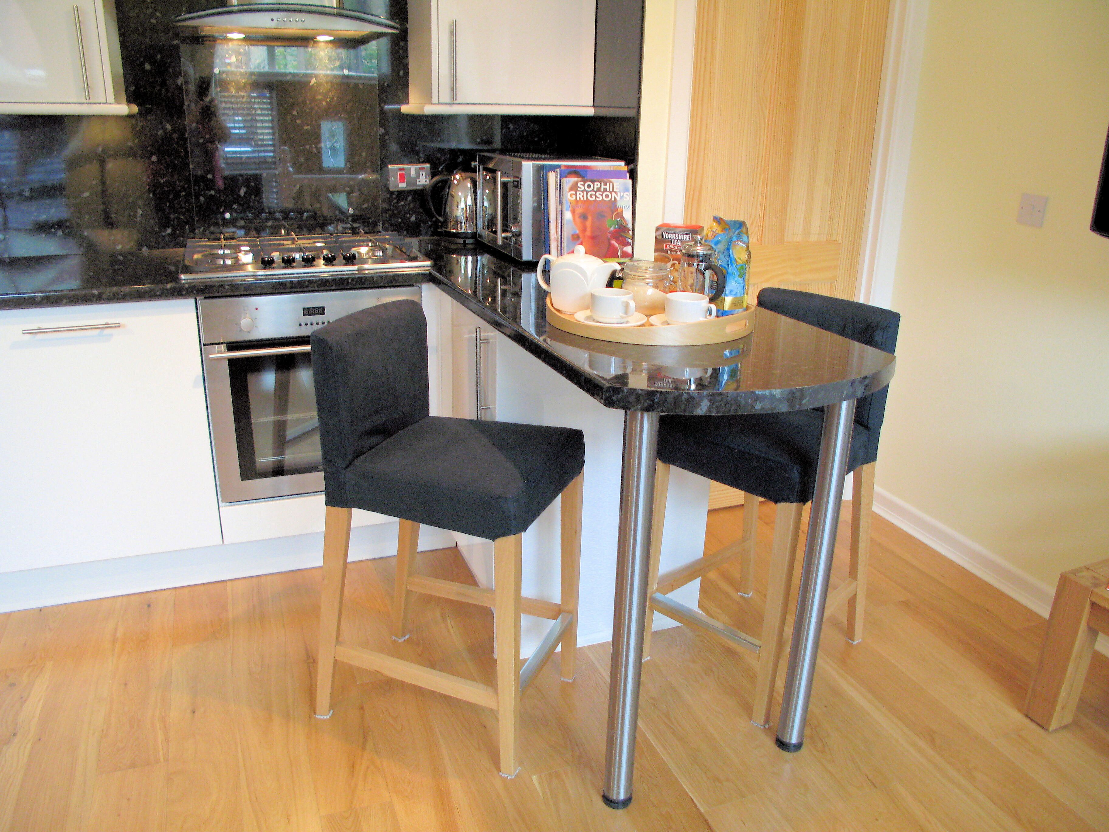 A compact kitchen with a gas stove, oven, microwave, and a small dining area with two chairs and a table.