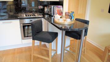 A compact kitchen with a gas stove, oven, microwave, and a small dining area with two chairs and a table.