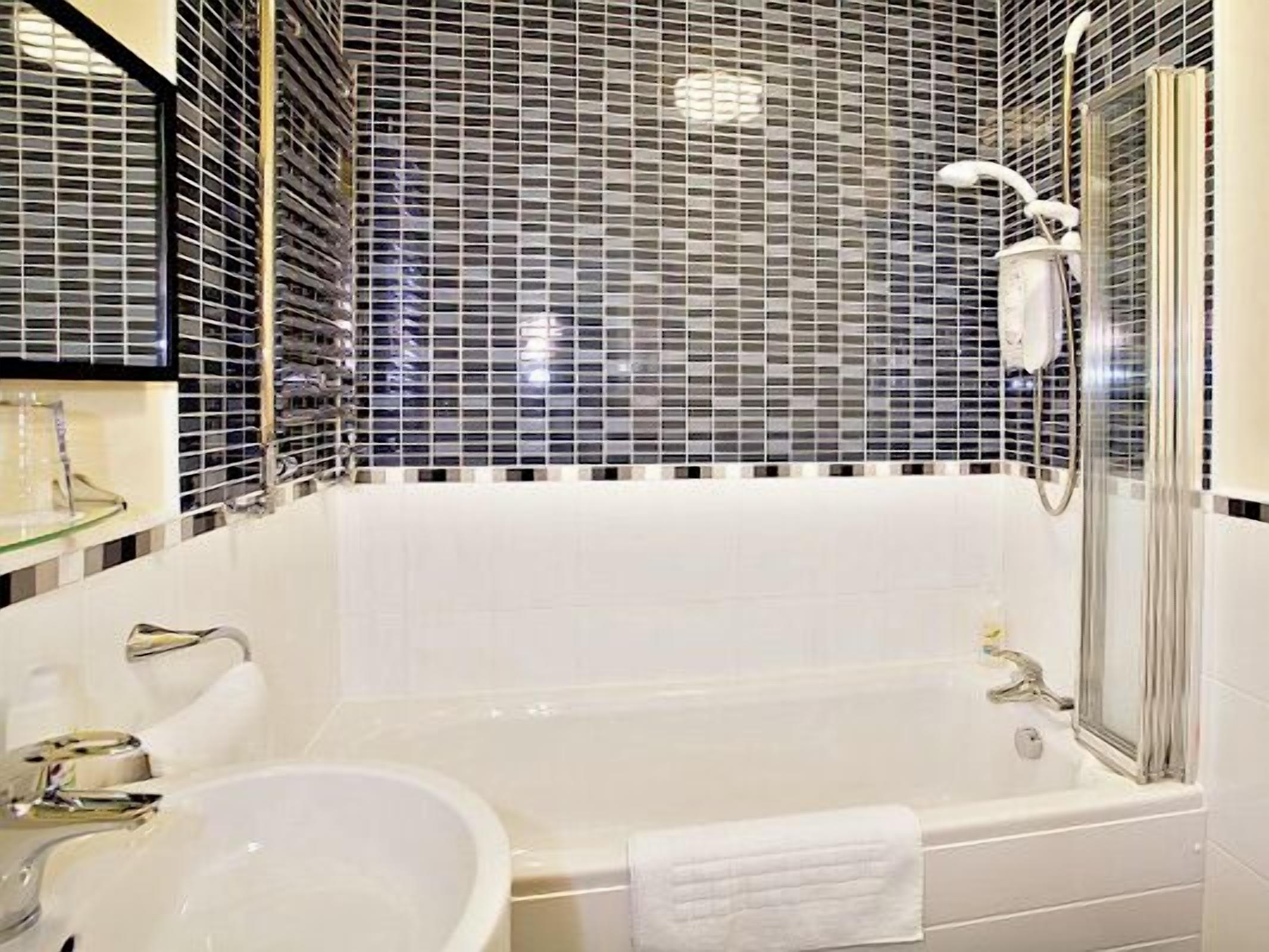 A modern bathroom with a large bathtub, a sink, and a glass-enclosed shower area.