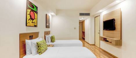 A modern hotel room with two beds, a flat-screen TV, and artwork on the walls.