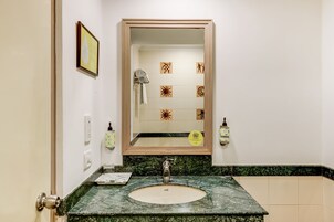 A bathroom with a marble sink, a mirror, and a towel rack.
