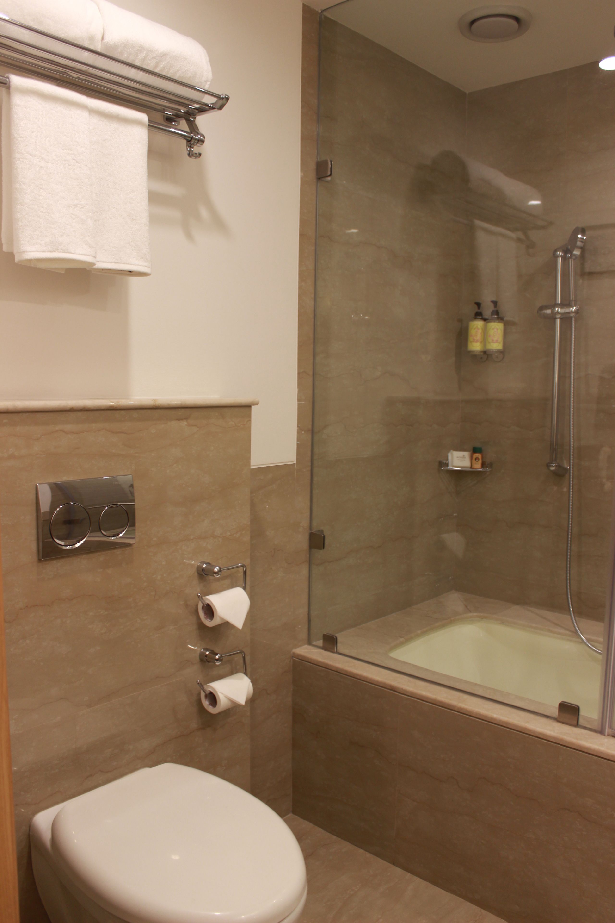 A bathroom with a toilet, a glass-enclosed shower, and a towel rack.