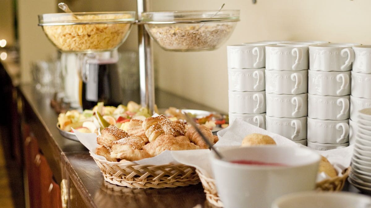 A buffet setup with various food items and stacked white cups.