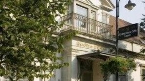 A building with a classical architectural style, featuring a balcony and a signboard. - Grand Rose SPA Hotel (Kuressaare)