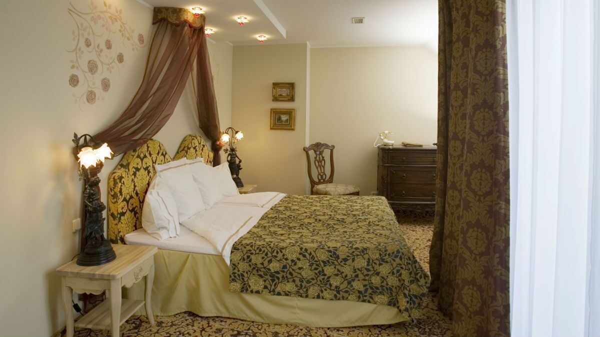 Un dormitorio con cama, mesitas de noche, cómoda y dosel.
