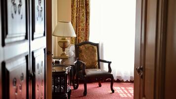 Una habitación interior con una silla de madera, una mesa con una lámpara y una cortina estampada.