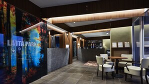 Un moderno vestíbulo de hotel con mostrador de recepción, zona de estar y bar.