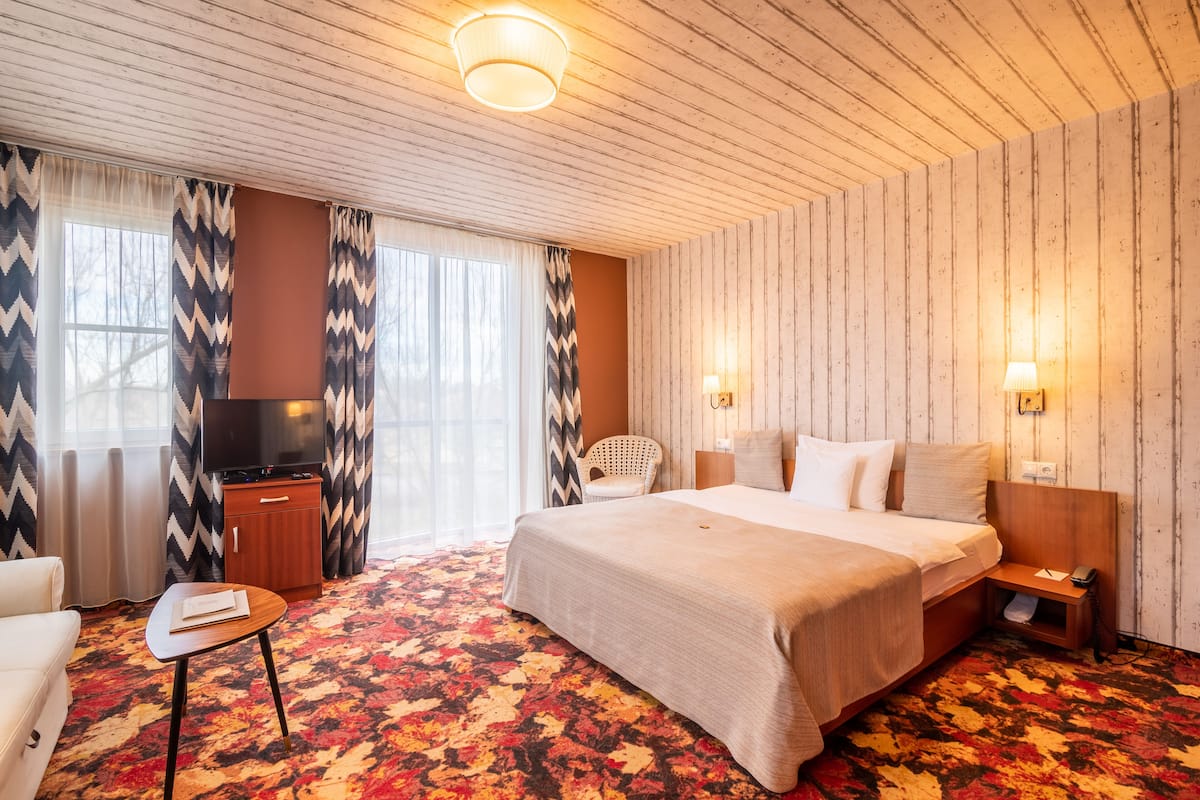 A hotel room with a large bed, a television, a desk, and a chair.