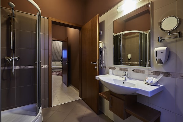 Un baño moderno con cabina de ducha de vidrio, un lavamanos blanco y un espejo grande.