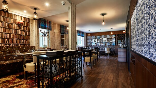 Una biblioteca amplia con estanterías, un bar de café y zonas de estar.