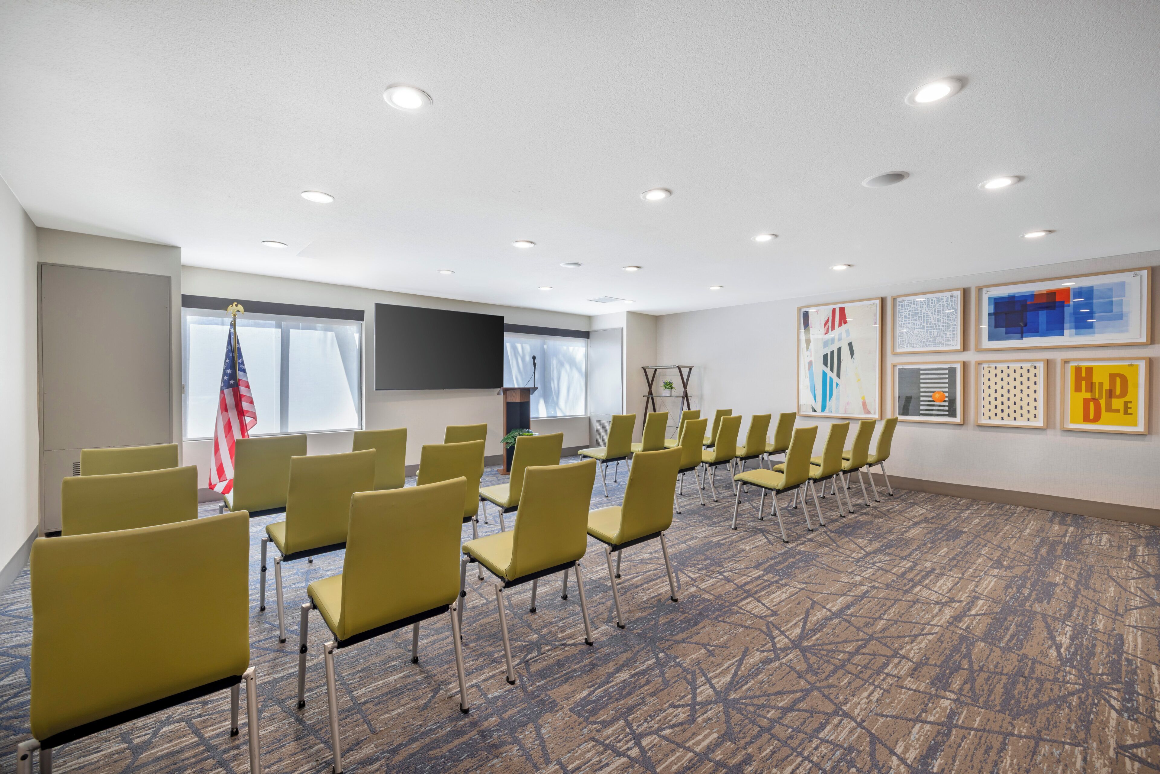 Un salón de conferencias con filas de sillas, un atril y una bandera.