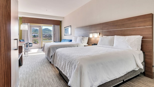 A hotel room with two beds, a desk, and a chair.