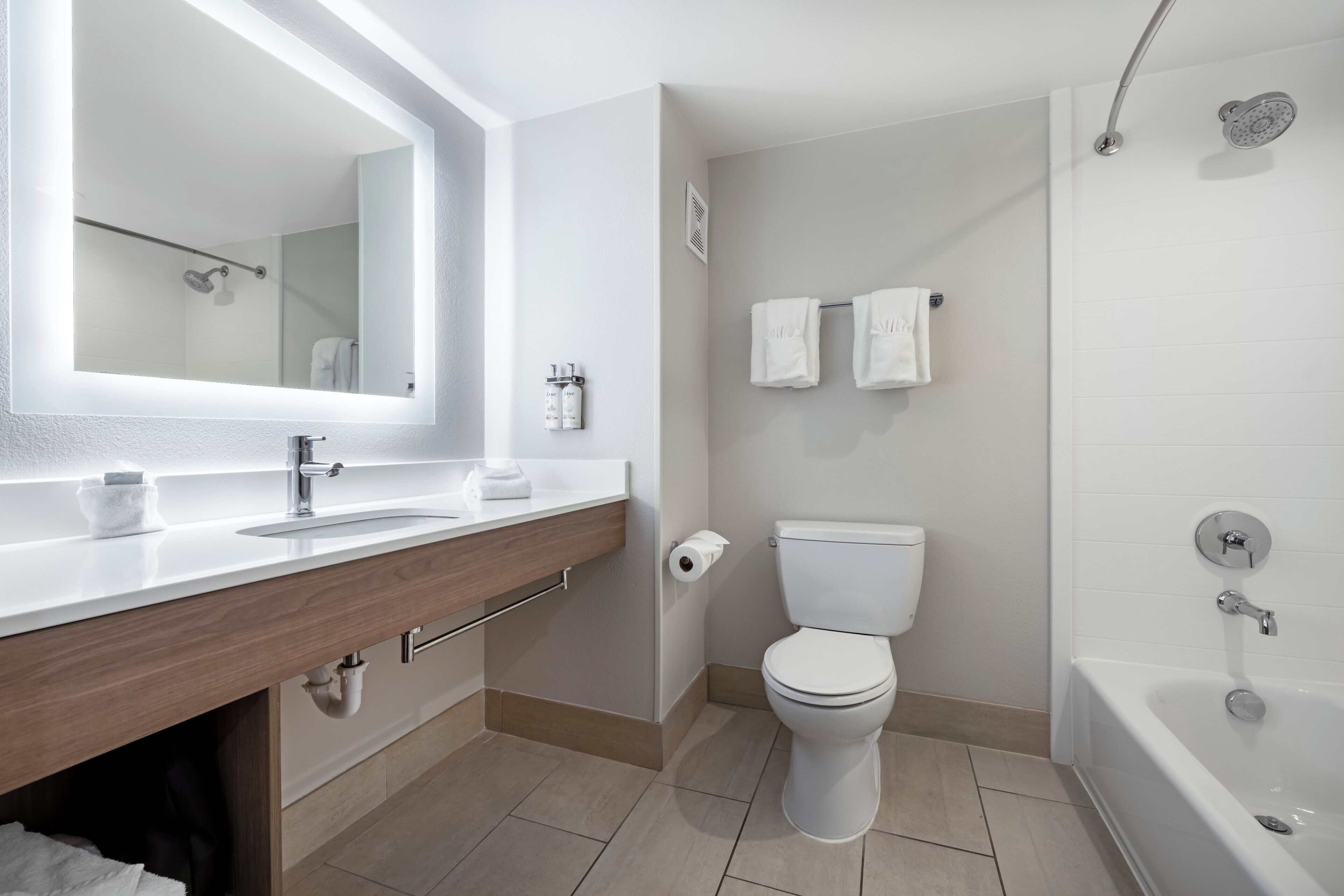 A modern bathroom with a sink, mirror, toilet, and shower.