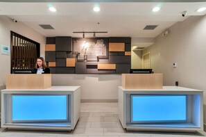 A hotel reception area with a modern design, featuring a reception desk, a staircase, and a sign for 'Hotel Inn Express & Suites'. - Holiday Inn Express & Suites, Lake Elsinore by IHG (Lake Elsinore)