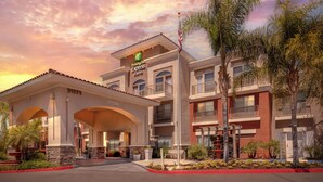 Un hotel Holiday Inn Express & Suites con cielo despejado y palmeras.