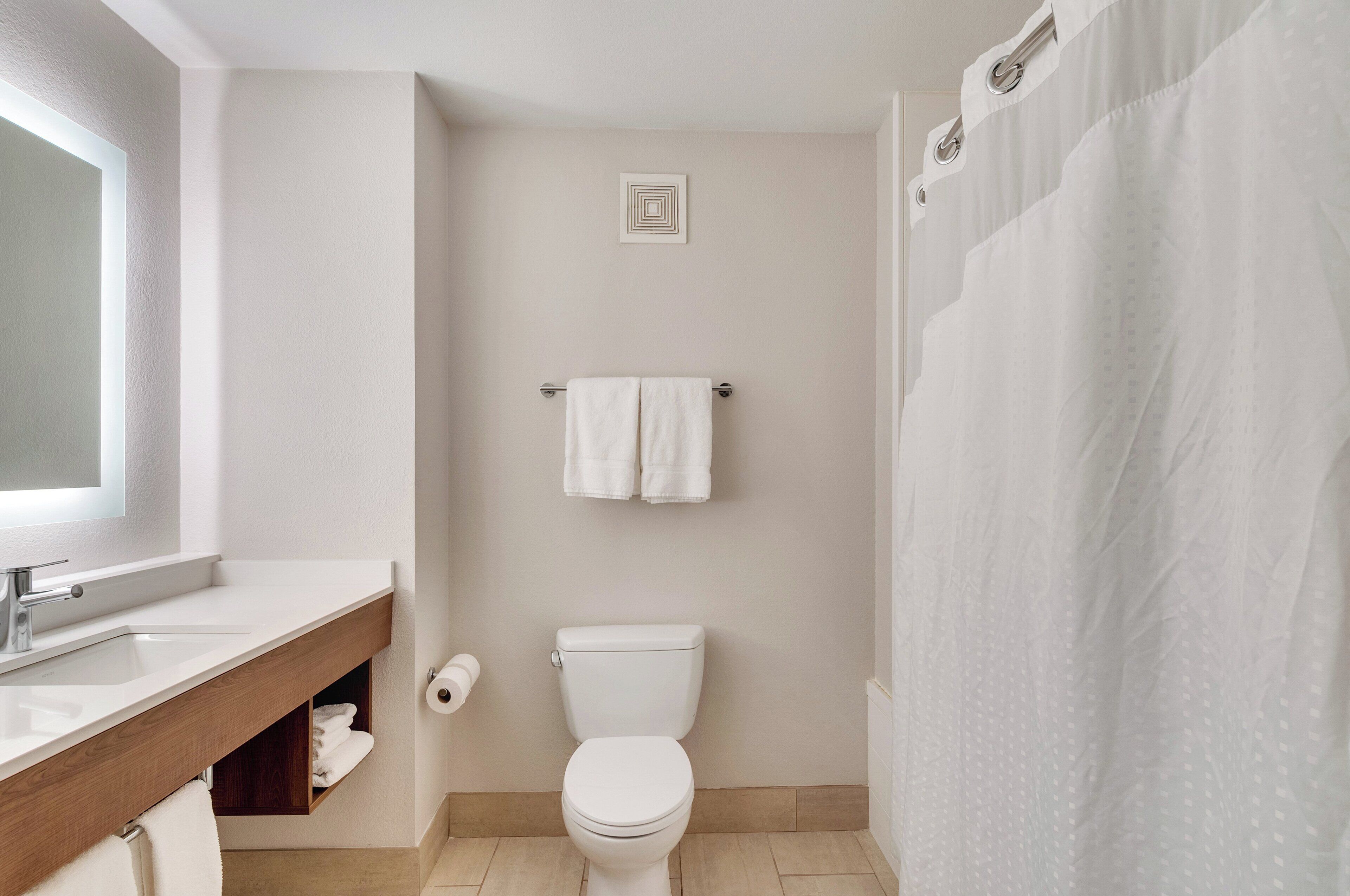 A bathroom with a white sink, toilet, and shower curtain.