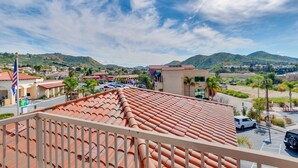 Un hotel con techos de tejas de barro, un estacionamiento y vistas a un paisaje montañoso.