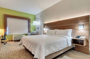A hotel room with a large bed, a bedside table with a phone and a lamp, a chair, a desk, and a window with blinds. - Holiday Inn Express & Suites, Lake Elsinore by IHG (Lake Elsinore)