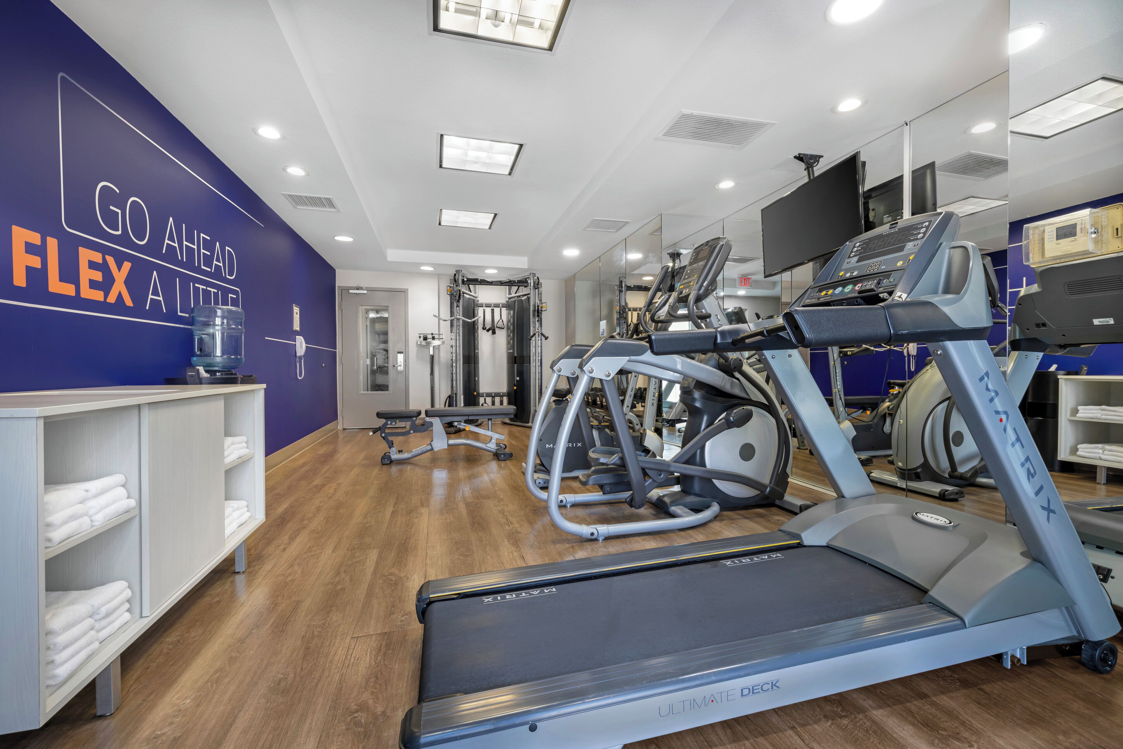 A gym with treadmills, weight machines, and a wall with motivational text.